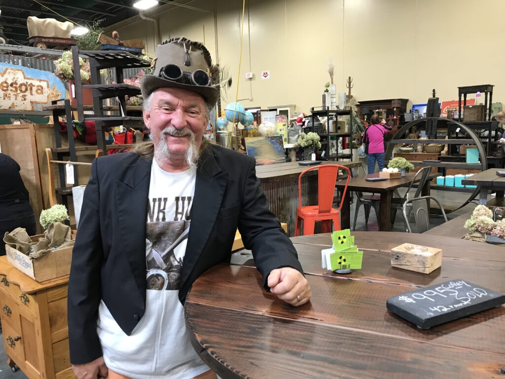 Mike Brown poses at his booth during the 2017 Junk Bonanza at Canterbury Park. He uses reclaimed barn wood mixed with industrial elements to create the furniture he sells.